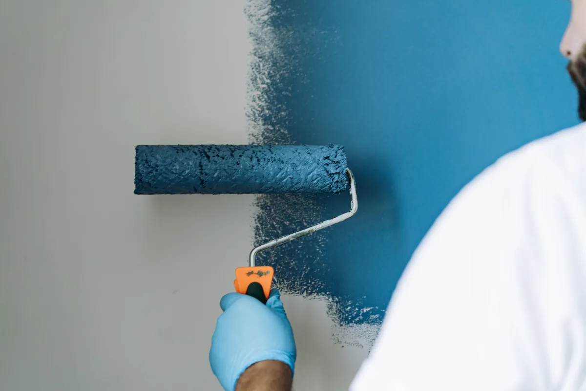 Roller laying a deep blue accent color onto an interior wall