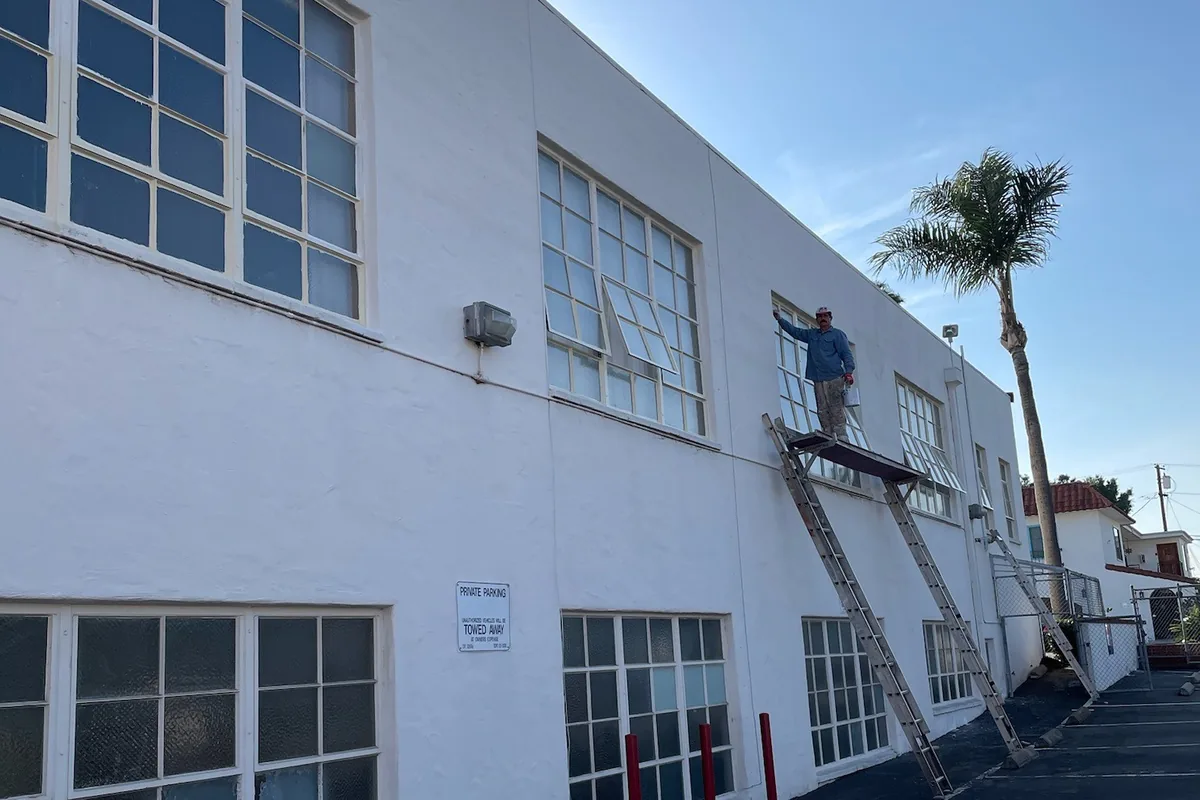 Crew member painting the upper wall from a ladder, a Tony's Painting job in San Diego County