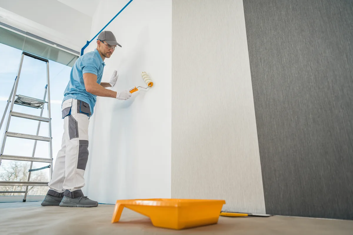 Painter rolling a white wall in a commercial space